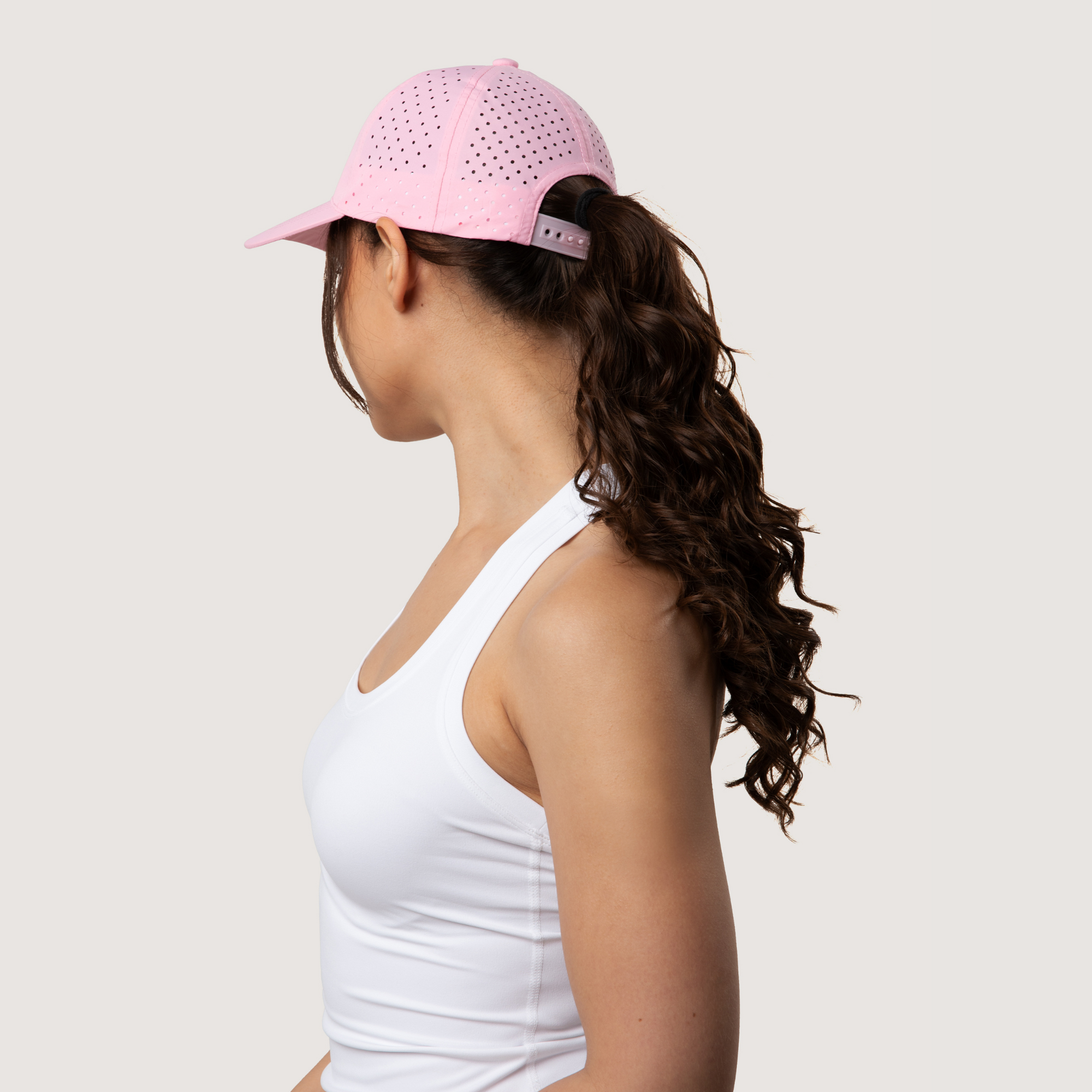 Person wearing a pink cap with cut-out patterns on a plain background