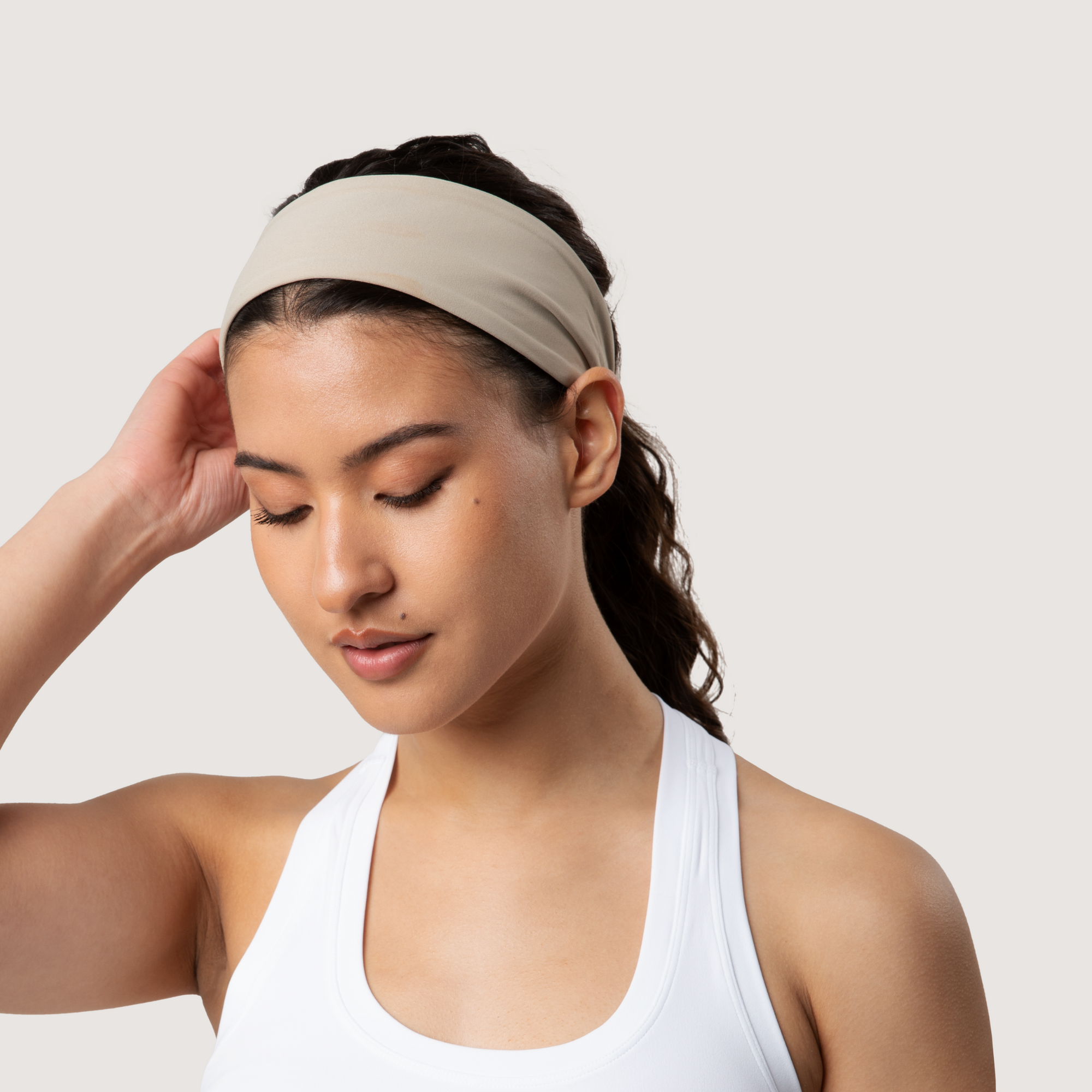 Woman wearing a beige headband against a plain background