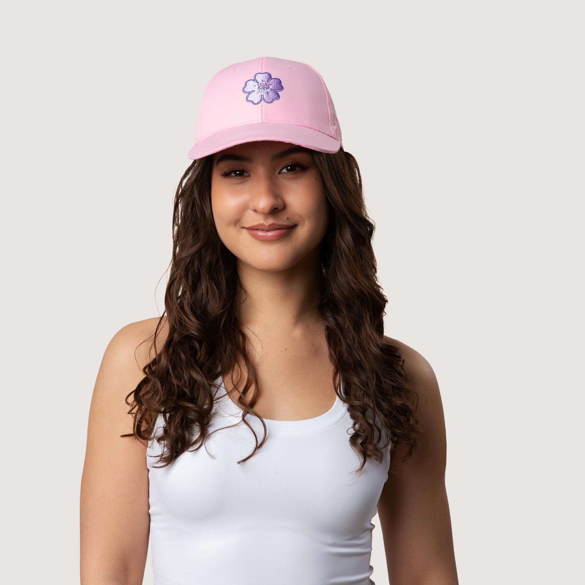 Woman wearing a pink cap with a flower design on a plain background