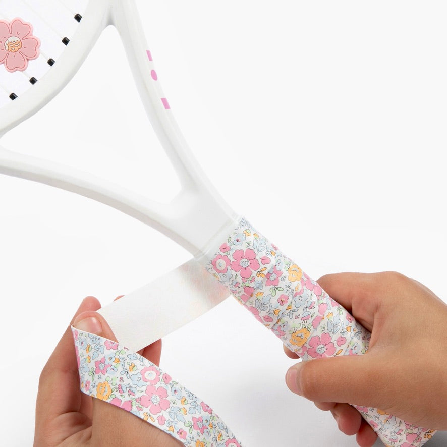Hand holding racket adorned with The Anneliese Collection Matching Tennis Overgrip and Dampener - Pink